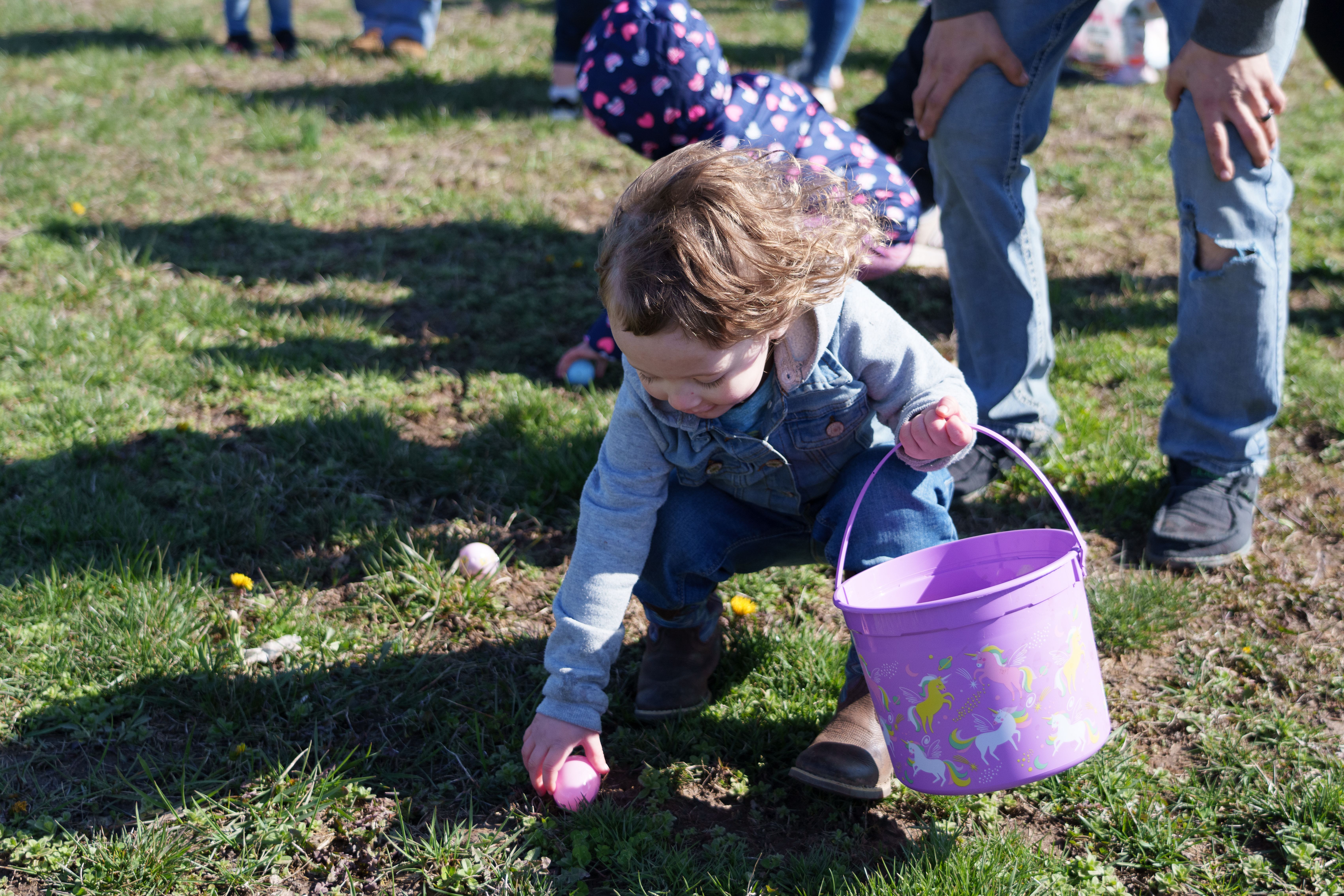 Photo of a child picking up a plastic egg