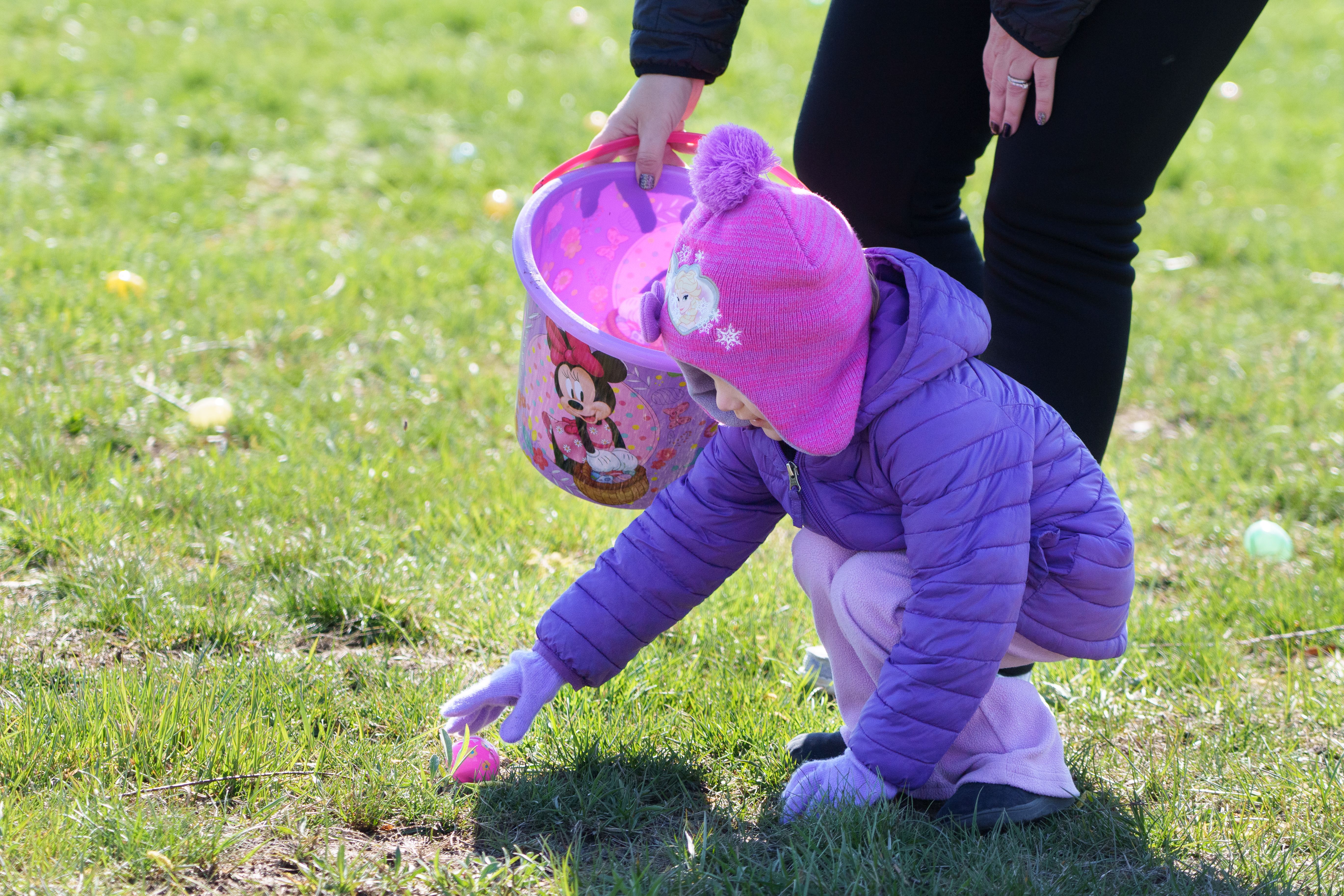 Photo of a child picking up a plastic egg