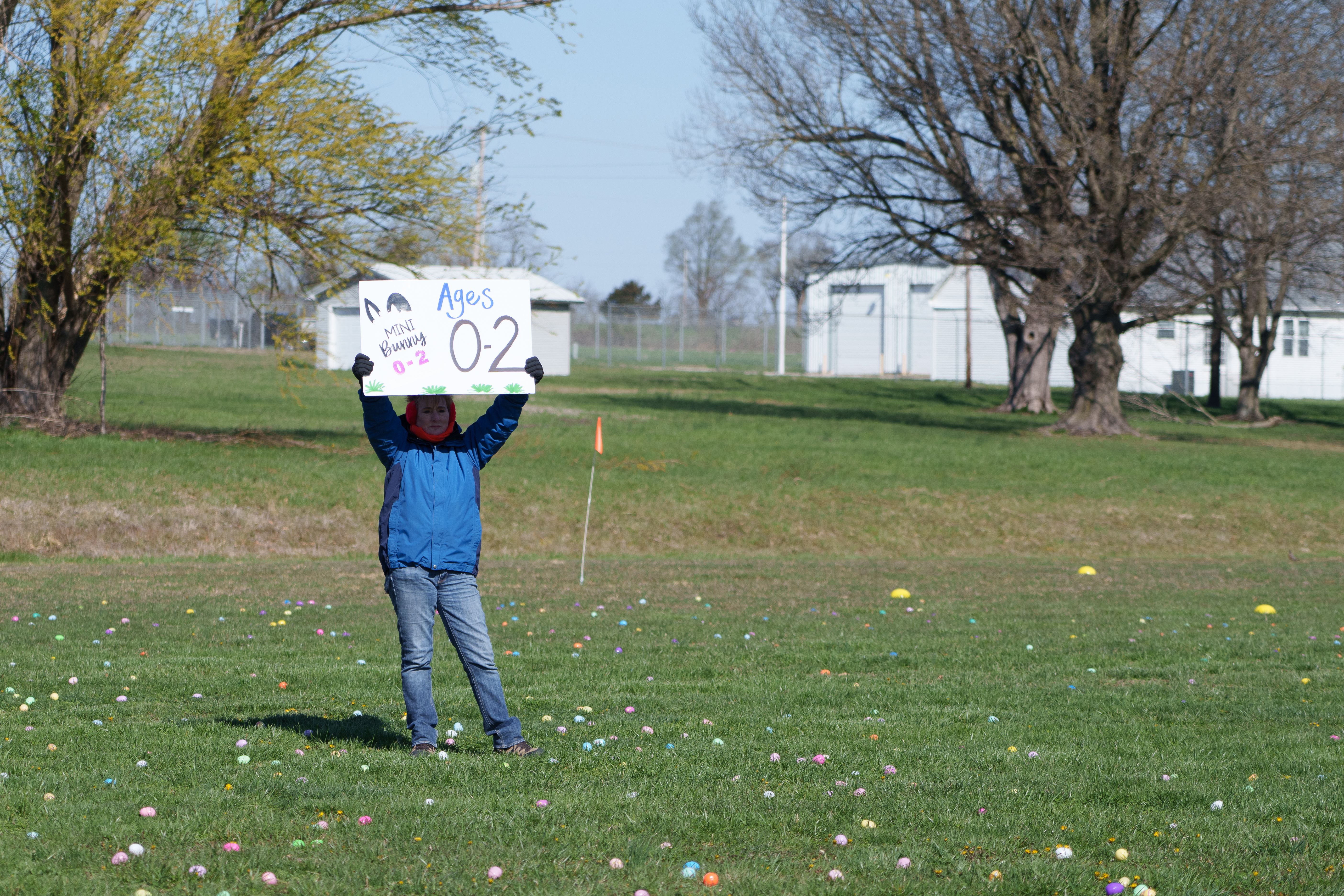 Photo of a woman holding a sign reading 'Ages 0-2' and 'Mini Bunny'