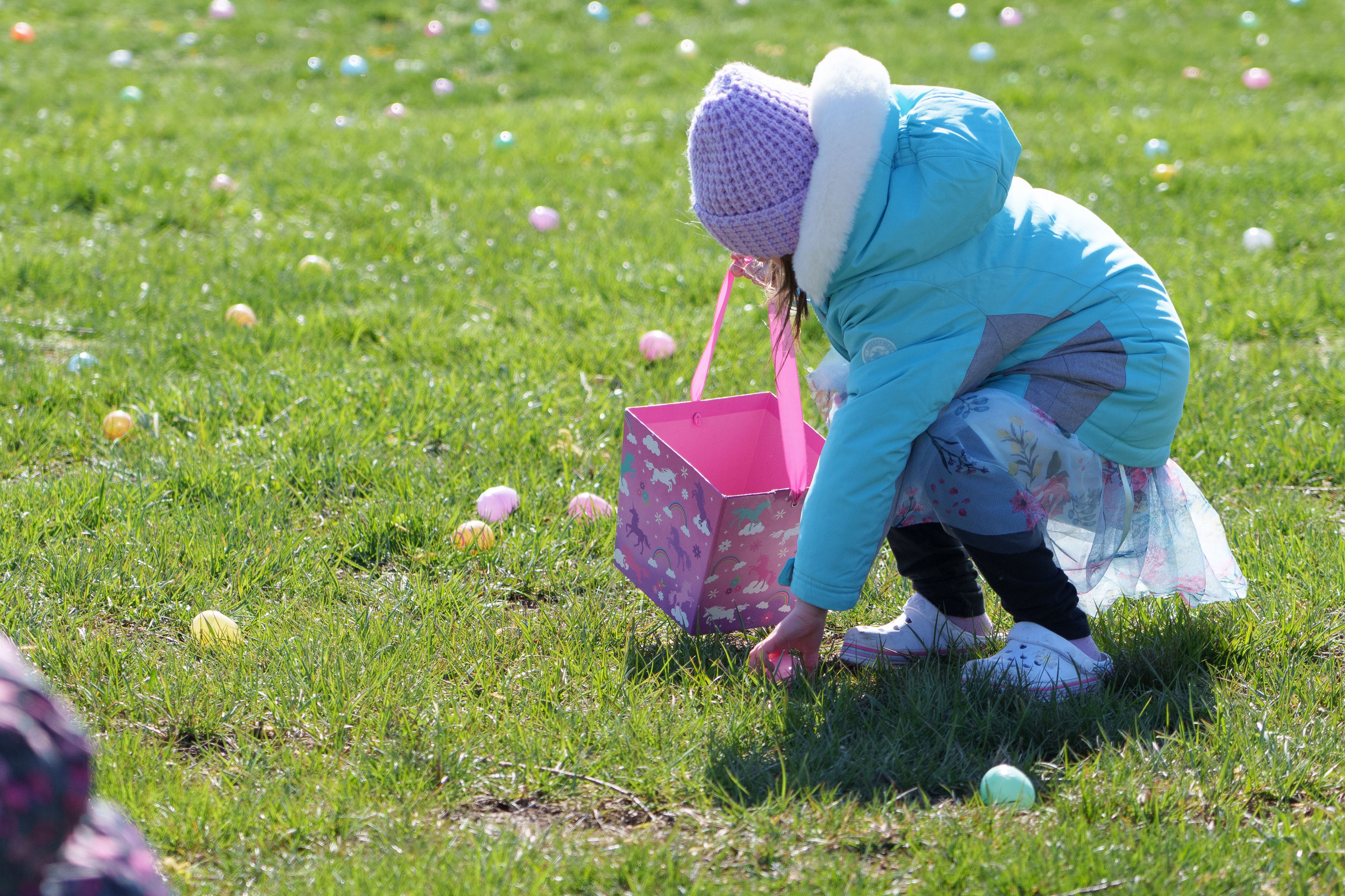 Photo of a child picking up a plastic egg